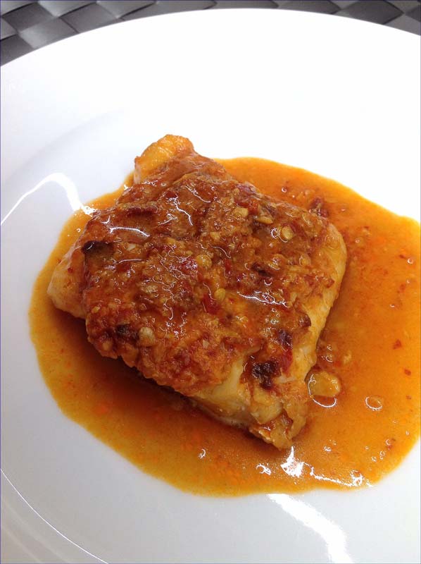 Plato blanco con bacalao, ajo y una salsa
