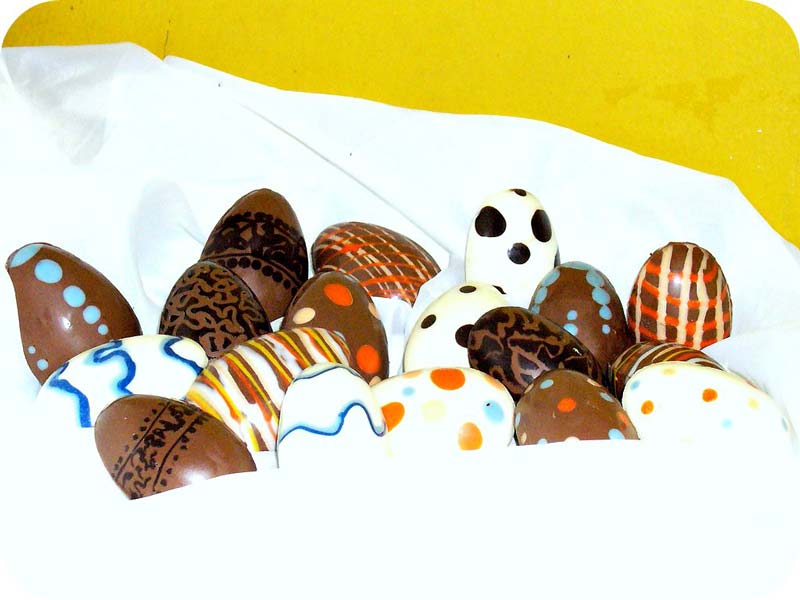 Cesta con muchos huevos de pascua de diferentes colores y decorados, todos ellos de chocolate