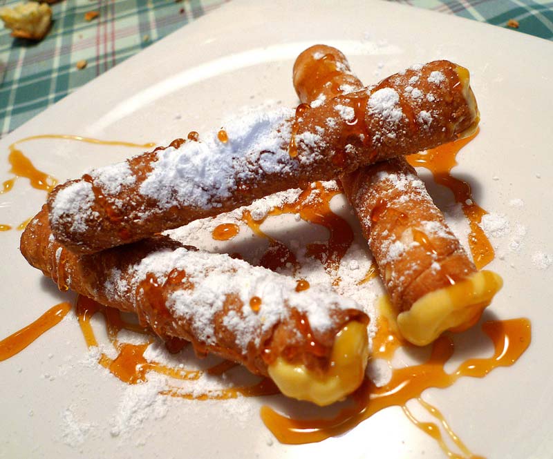 Tres pestiños de miel y azúcar sobre un plato blanco