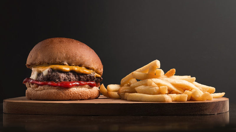 tabla de madera con una hamburguesa con patatas fritas en la derecha