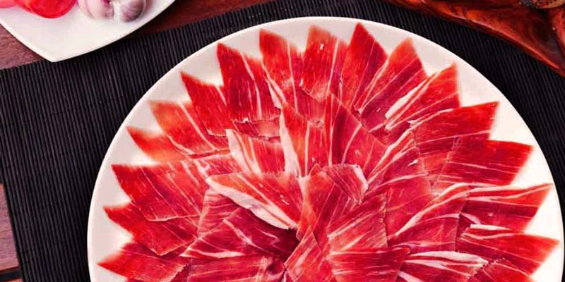 un plato blanco redondo con láminas de jamón serrano