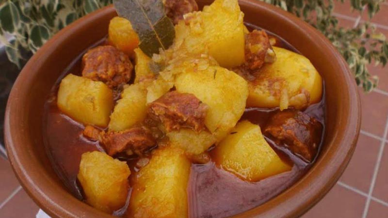 una bandeja con patatas y chorizo con salsa