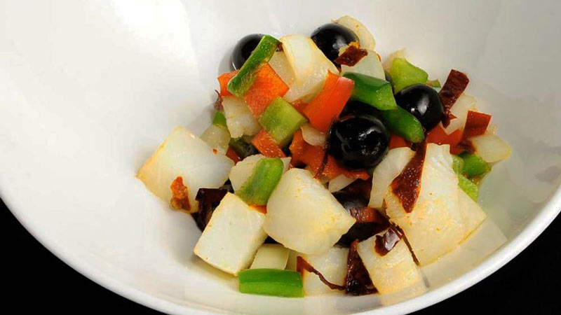 un bol blanco con patatas, pimientos y aceitunas