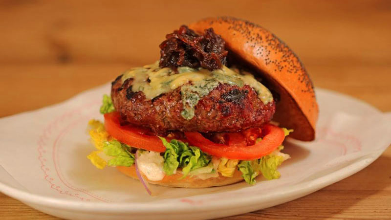 una hamburguesa con carne y ensalada en un plato blanco redondo