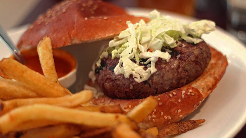 una hamburguesa con lechuga y unas patatas fritas delante