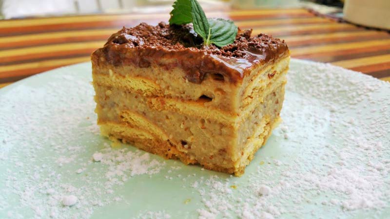 un trozo de tiramisú con una hoja verde y en un plato verde