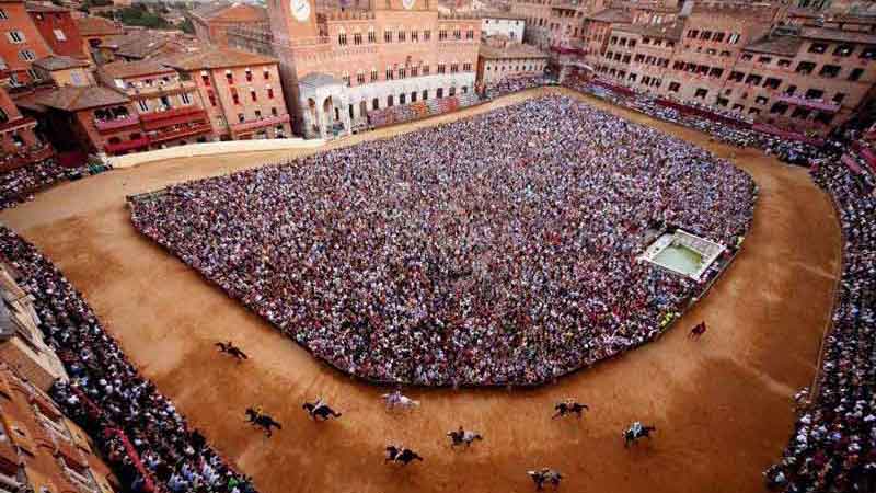 una pista donde cabalgan caballos y con mucha gente