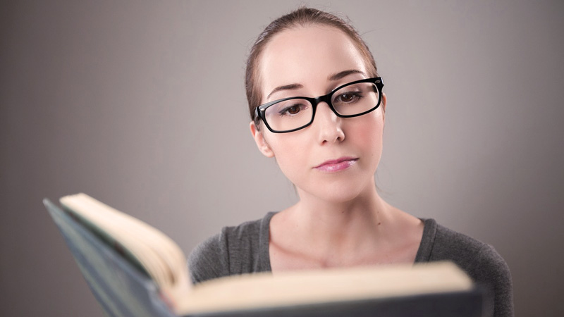 una mujer con gafas de pasta que está leyendo un libro