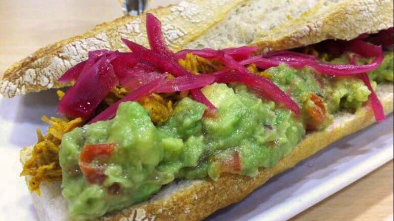 bocadillo con guacamole que está sobre un plato blanco