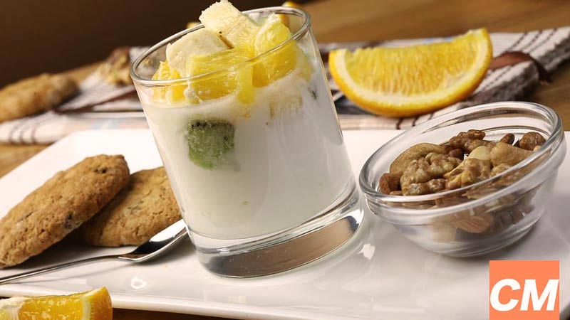 plato blanco rectangular blanco con galletas, un bol con nueces y un vaso con yogur y fruta