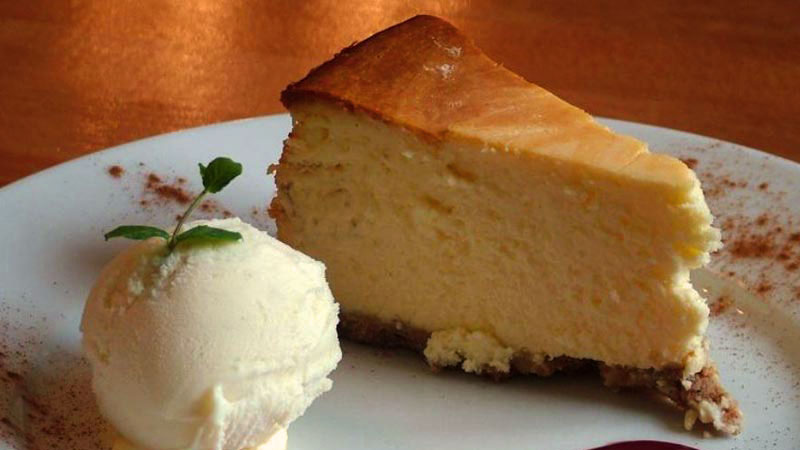 plato blanco con una porción de pastel con una bola de helado en la izquierda