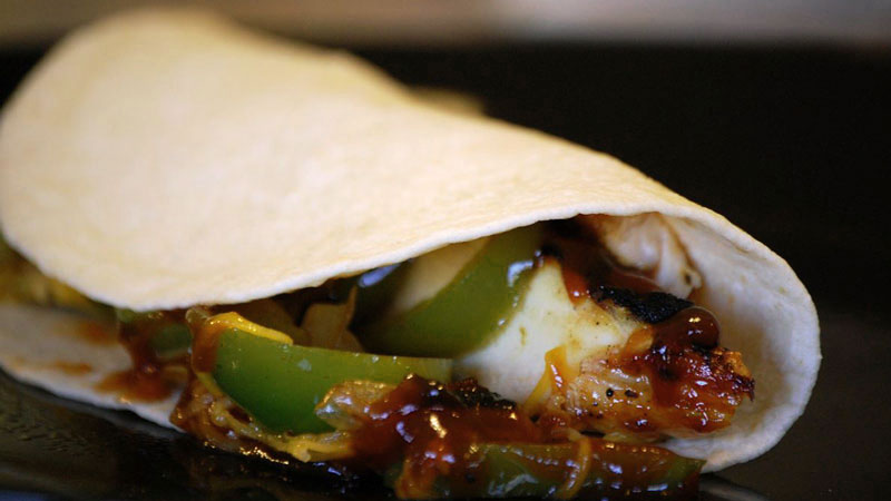 burrito con pimientos y salsa sobre un fondo negro