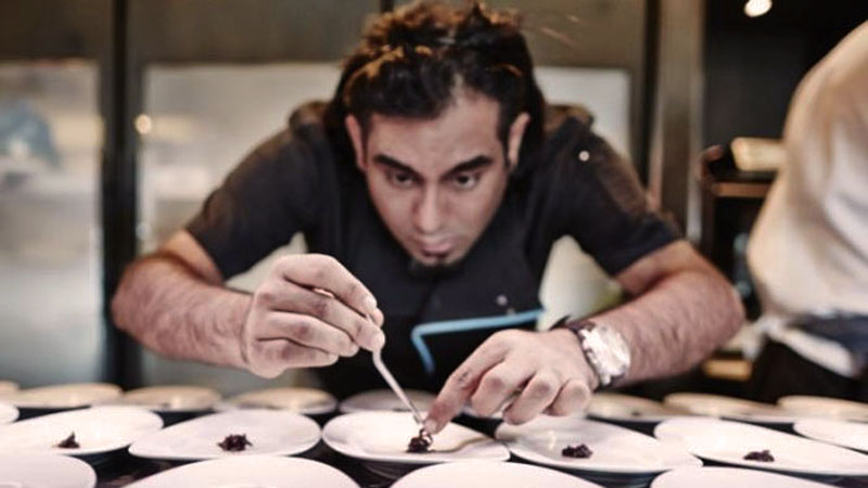 un cocinero preparando un plato de los muchos que hay en la mesa