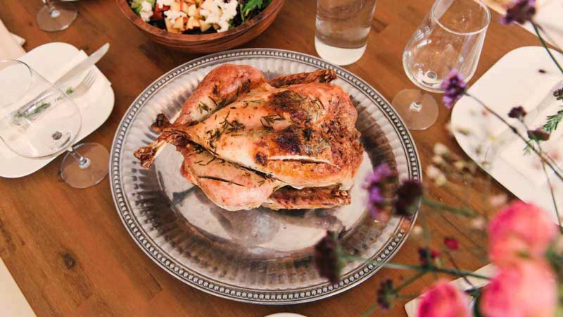 una bandeja metálica con un pollo con especias y rodeado de copas