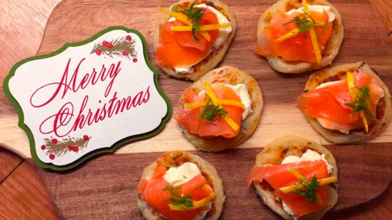 tabla de madera con aperitivos de salmón con un cartel al lado de Navidad