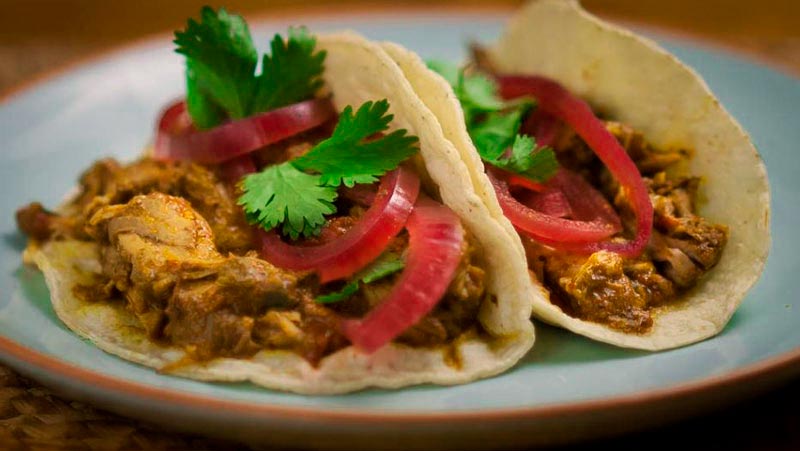 dos panes con relleno de carne y cebolla sobre un plato azul