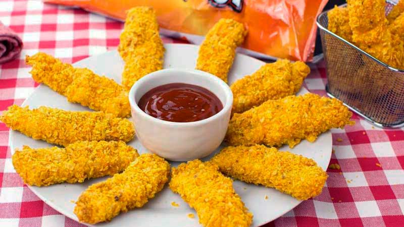 plato blanco con palitos de pollo rebozado que tienen en el centro un bol de salsa