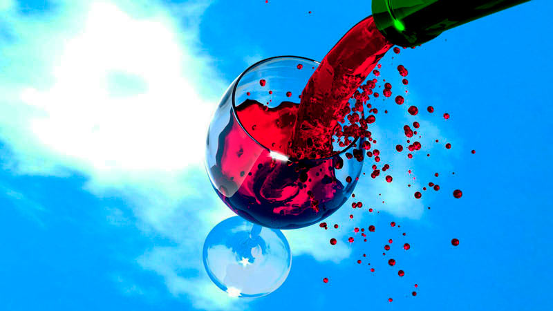 una copa de cristal y una botella que echa vino sobre esta, todo ello sobre un fondo de cielo azul