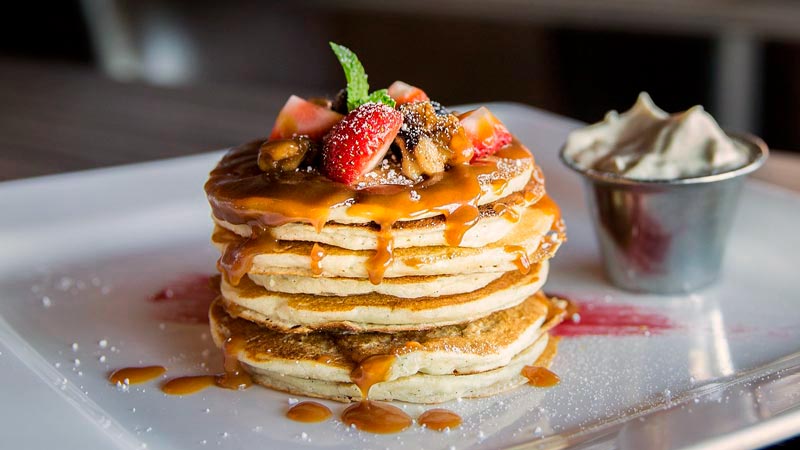 tortillas con frutas encima y sirope sobre un plato cuadrado blanco