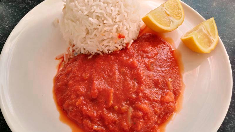 plato blanco con tomate, arroz basmati y dos rodajas de limón