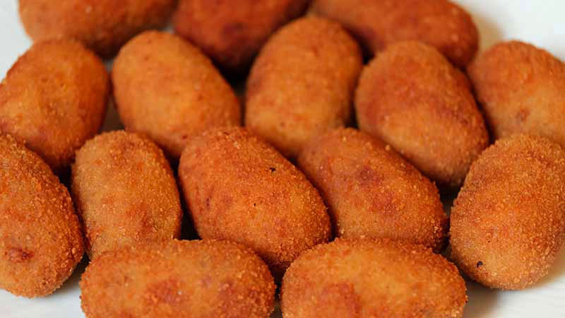 varias croquetas sobre un fondo blanco que ocupan todo el plano