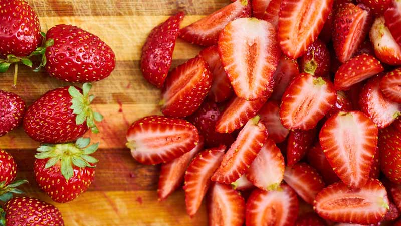 fresas enteras a la izquierda y fresas cortadas a la derecha