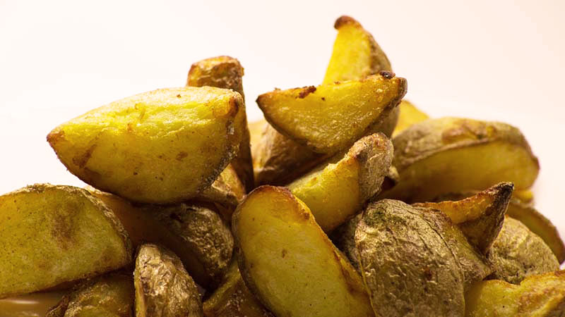 patatas cortadas en gajos con piel sobre un fondo blanco