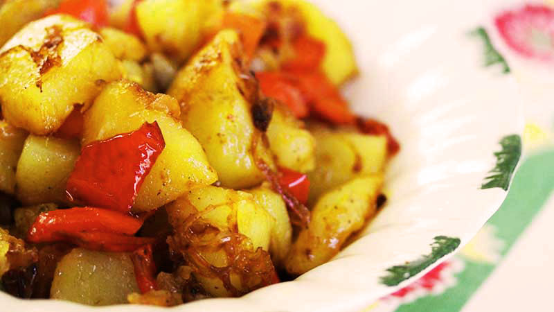 plato blanco con trozos de patatas con pimientos rojos