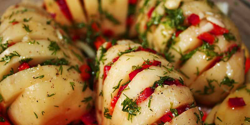 patatas peladas con cortes horizontales, los cuales están rellenos de pimientos rojos