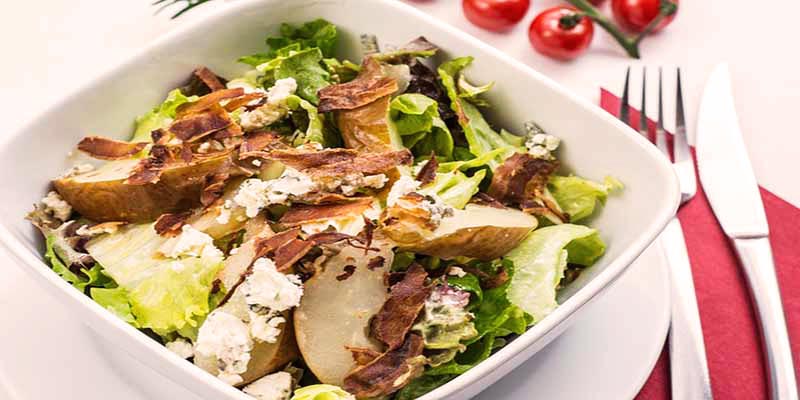 plato blanco cuadrado con ensalada y unos cubiertos metálicos en la derecha