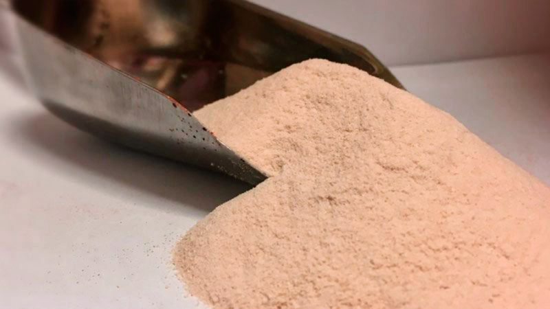 una espátula de metal que tiene harina sobre un fondo blanco