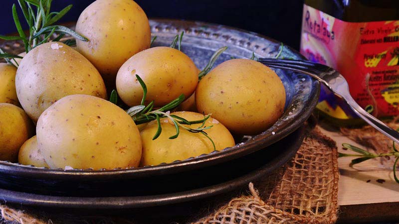 patatas rn un plato negro con un tenedor a un lado y con un mantel de hilos debajo