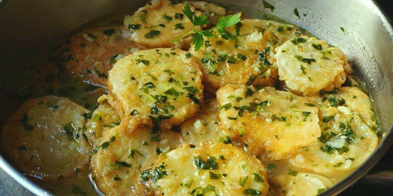 patatas cortada en láminas gruesas en una sartén con especias