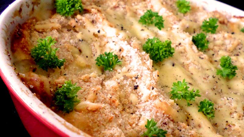 plato rojo con lasaña, la cual tiene unas hojas verdes encima