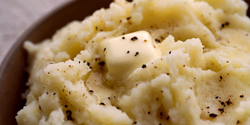 plano detalle de un puré en un bol marrón y con un cuadrado de queso encima
