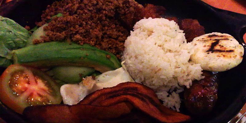 plato negro con arroz, huevo, tomate, carne picada y chorizo