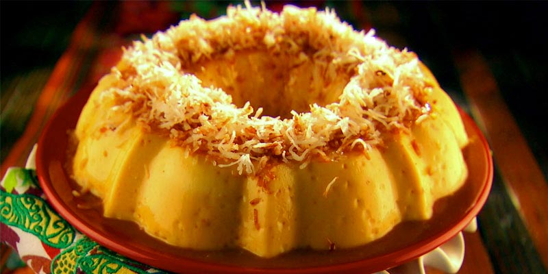 flan redondo con agujero en medio y con trozos de coco encima sobre un plato rojo