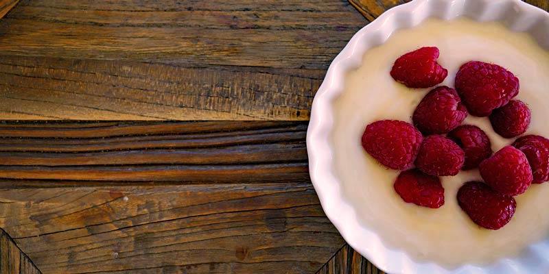 plato con yogur y frutos rojos sobre una mesa de madera