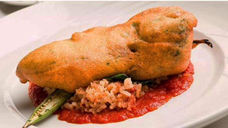 chile relleno con una base de arroz y tomate en un plato blanco