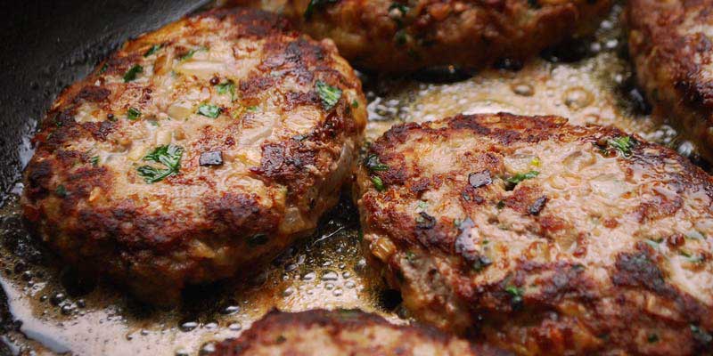 hamburguesas cocinándose en una sartén negra