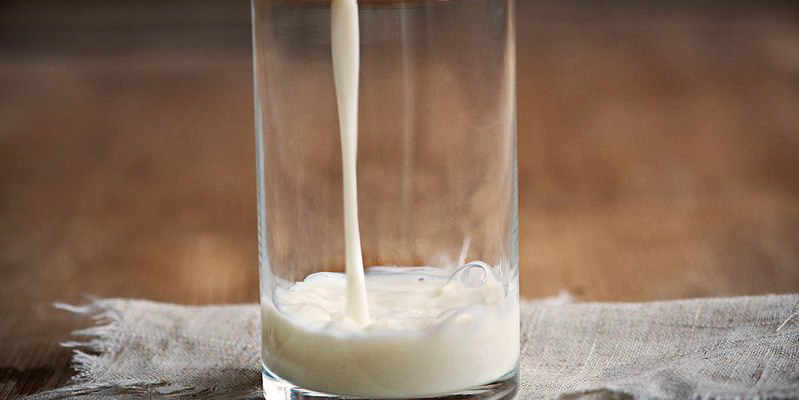 vaso de cristal con un chorro de leche llenándolo