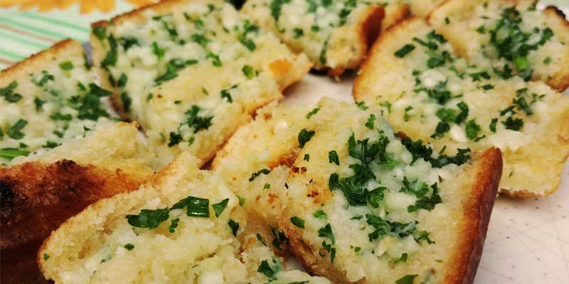 pan con ajo y perejil sobre una mesa con mantel a rayas