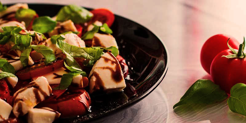 plato negro con ensalada de queso, tomate, lechuga