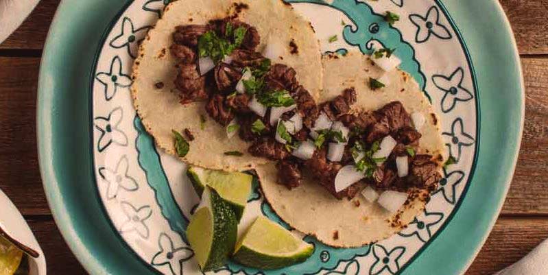 dos tacos en un plato con dibujos de flores azules sobre una mesa de madera