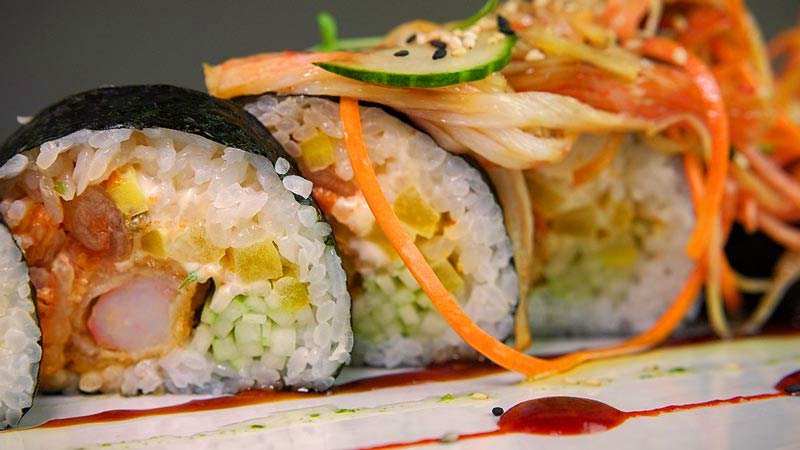 sushi puesto en fila con ingredientes como zanahoria encima