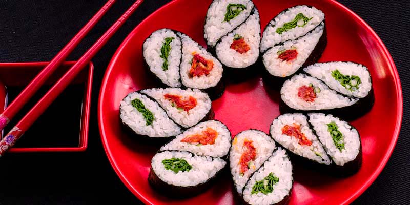 sushi en círculo sobre un plato rojo con palillos también rojos a un lado