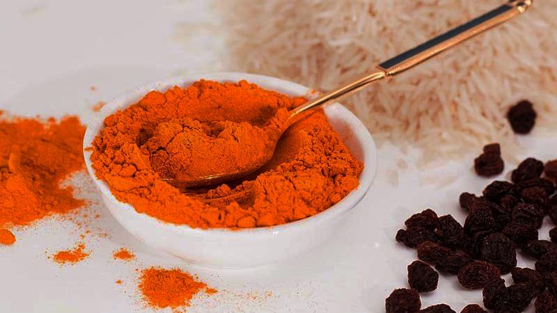curry en un bol pequeño blanco con una cuchara y con arroz y pasas alrededor