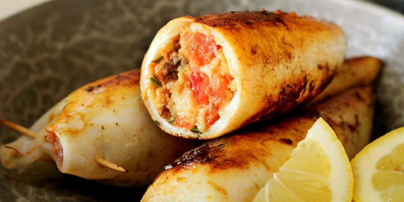 chipirones con relleno y en un plato gris con limones cortados
