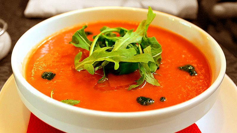 bol blanco con gazpacho naranja, el cual tiene hojas verdes en el centro
