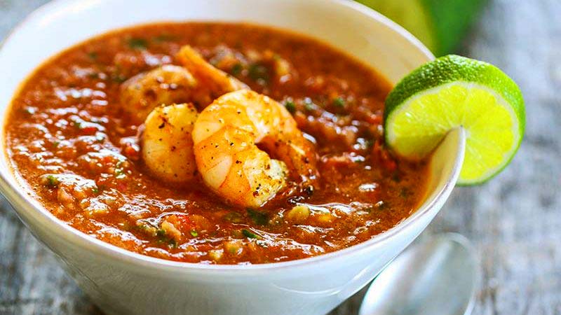 gazpacho rojo en un bol blanco con una rodaja de lima en el borde
